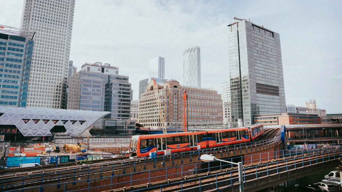 A vibrant view of London's Canary Wharf with modern skyscrapers and a passing train.