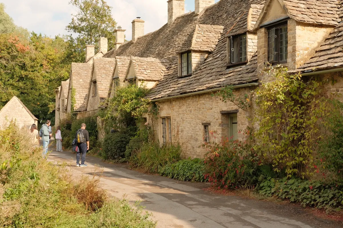 Charming stone cottages line a quiet street in the Cotswolds, England during fall.