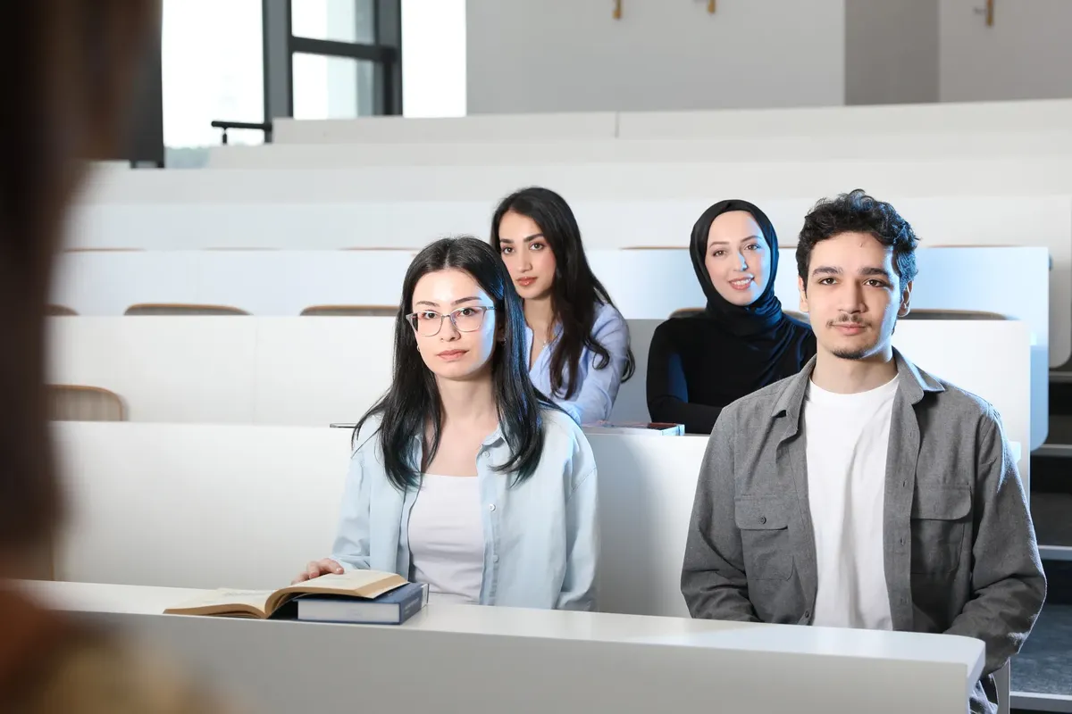 Group of diverse university students attending a class session in a modern lecture hall.