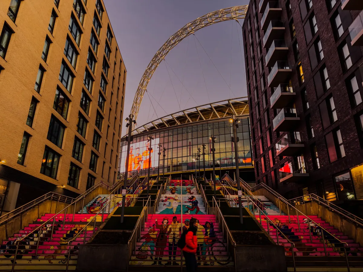 Colorful steps leading to Wembley Stadium between modern buildings at sunset in London.